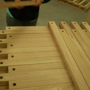 ceci est la photo d'une personne qui empile sur une palette des morceaux de bois usiné