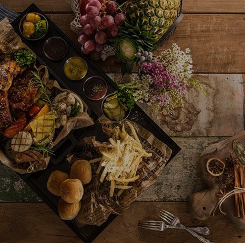 ceci est la photo d'une table avec divers aliments, viandes, légumes, fruits, sauces et un bouquet de fleurs