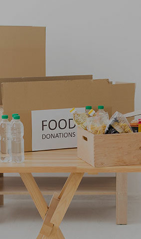ceci est la photo d'une table sur laquelle il y a, des bouteilles d'eau, de la nouriture dans une caisse et un carton où il y a inscrit food donations